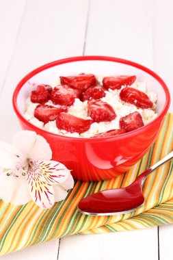 Beyaz ahşap masa üzerine dilimlenmiş çilek kırmızı kase süzme peynir