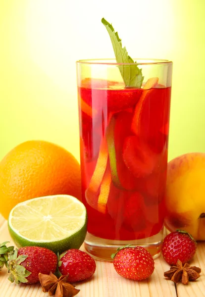 Erfrischende Sangria im Glas mit Früchten, auf Holztisch, auf grünem Hintergrund — Stockfoto