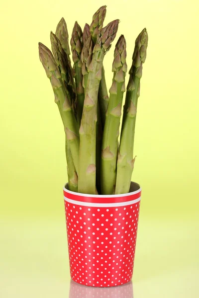 Fresh asparagus in colorful pot on green background — Stock Photo, Image