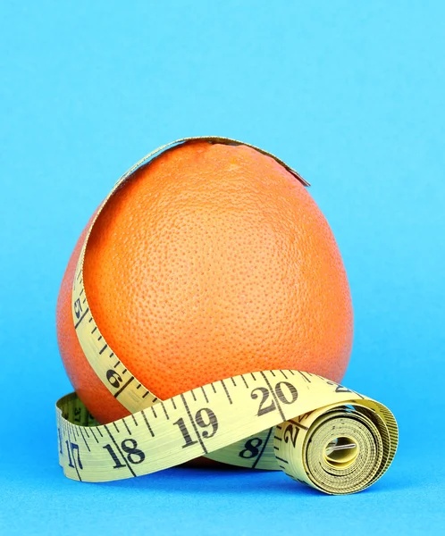 Orange with measuring tape on blue background — Stock Photo, Image