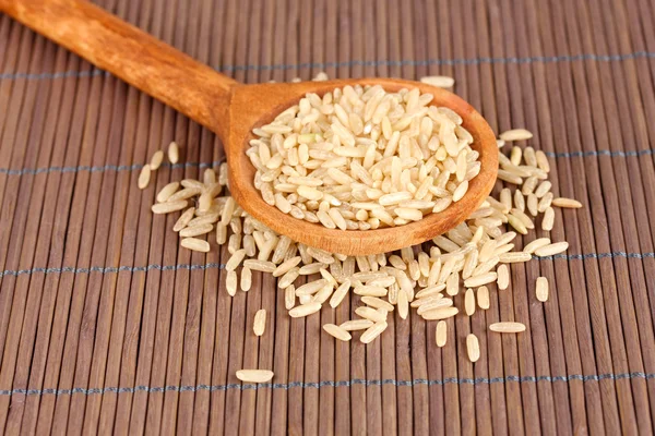 Рис в дерев'яній ложці на бамбуковому килимку — стокове фото