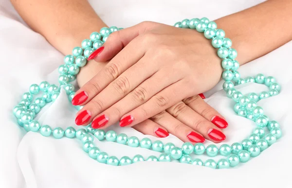 Female hands holding beads on color background — Stock Photo, Image