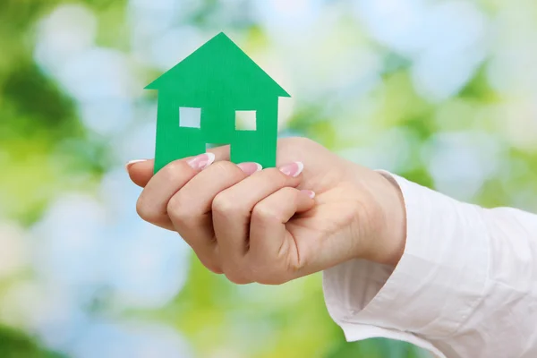 Concetto: mano donna con casa di carta su sfondo verde, primo piano — Foto Stock