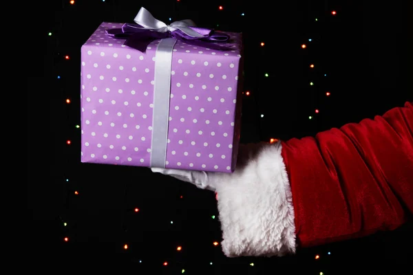 Babbo Natale mano in possesso di scatola regalo su sfondo luminoso — Foto Stock