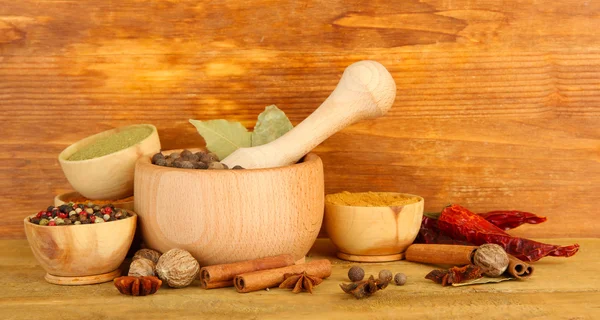 Mortar, bowls and spoons with spices, on wooden background — Stock Photo, Image