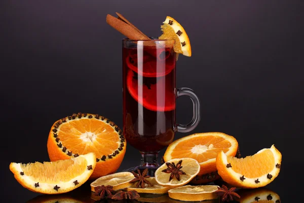 Duftender Glühwein im Glas mit Gewürzen und Orangen auf violettem Hintergrund — Stockfoto
