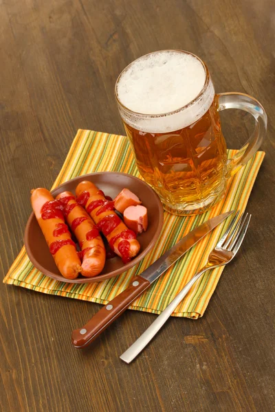 Пиво и колбасы на деревянном фоне — стоковое фото