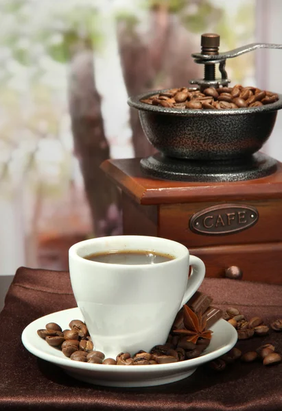 Cup of coffee, grinder and coffee beans in cafe — Stock Photo, Image