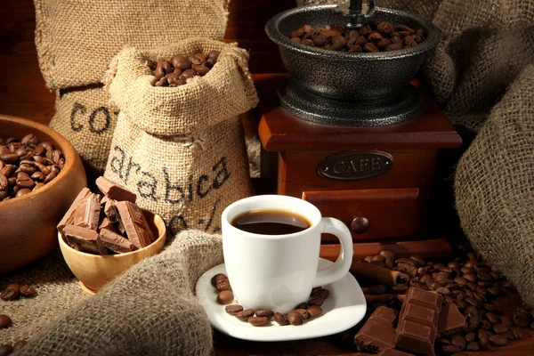 Coffee grinder and cup of coffee on brown wooden background — Stock Photo, Image