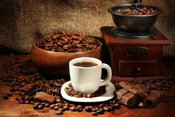 Kaffekvarn och kopp kaffe på säckväv bakgrund — Stockfoto