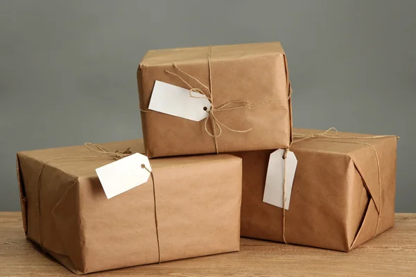 Paketkästen mit Kraftpapier, auf Holztisch auf grauem Hintergrund — Stockfoto