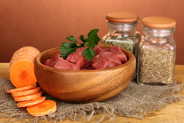 Raw beef meat marinated with herbs and spices on wooden table on brown background — Stock Photo, Image