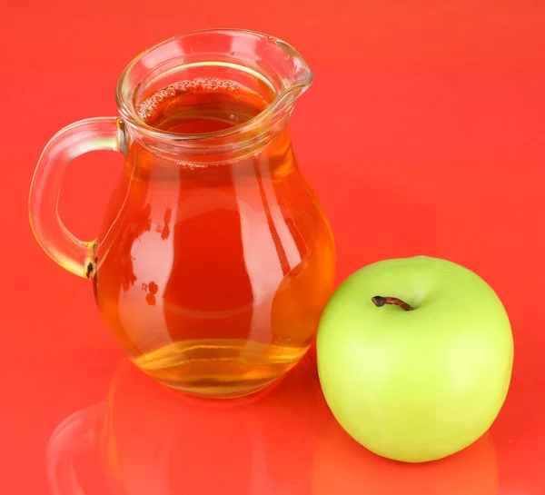 Elma suyu ve elma renk arka plan üzerinde tam sürahi — Stok fotoğraf