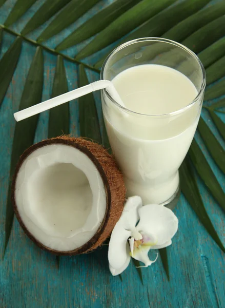 Coco com copo de leite, sobre fundo de madeira azul — Fotografia de Stock