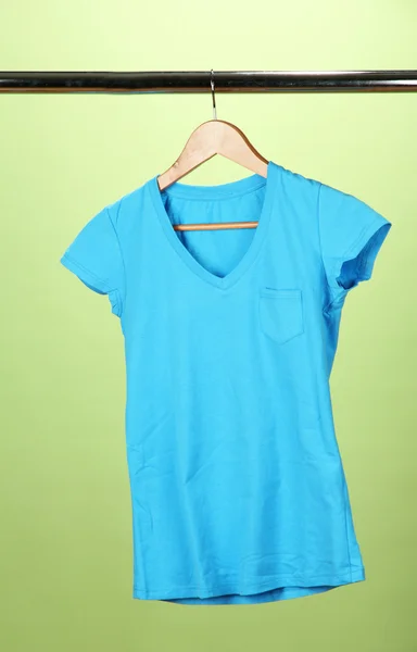 T-shirt on wooden hanger, on green background — Stock Photo, Image