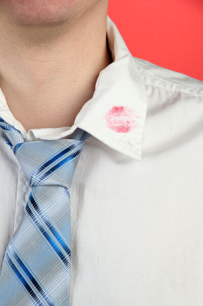 Lipstick kiss on shirt collar of man, on red background