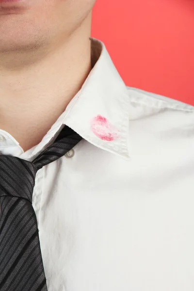 Lipstick kiss op de kraag van het shirt van de mens, op rode achtergrond — Stockfoto