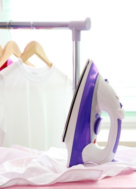 Kumaş arka planda elektrikli ütü ve gömlek.