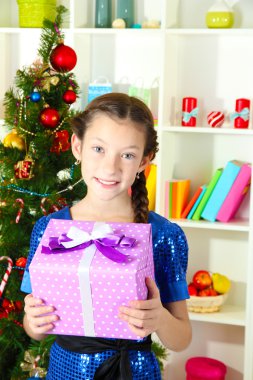 hediye kutusu Noel ağacının yakınında tutan küçük bir kız