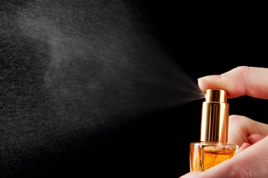 women's perfume in bottle and spraying, on black background clipart