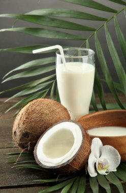 Coconut with glass of milk, on wooden table, on grey background clipart