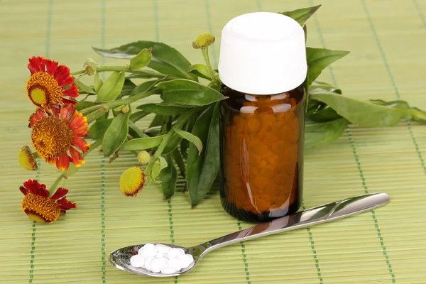 Frasco de medicamento com comprimidos e flores em esteira de bambu — Fotografia de Stock