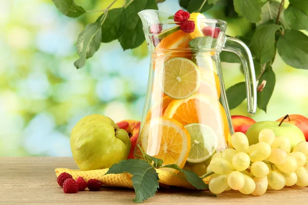 Jar with citrus fruits and raspberries, on green background — Stock Photo, Image