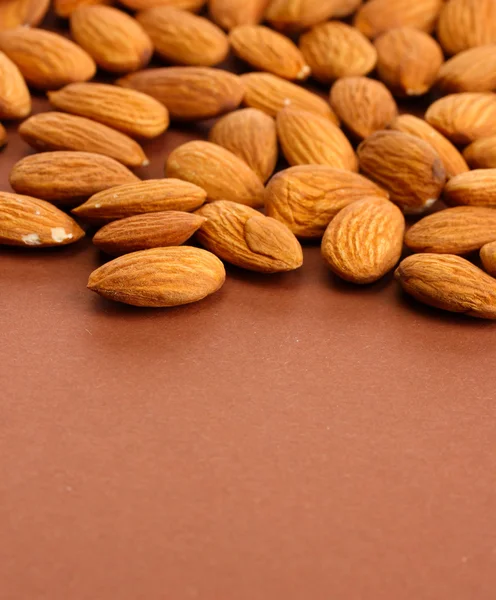 Tasty almond nuts, on brown background — Stock Photo, Image