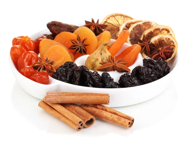 Dried fruits with cinnamon and anise stars on plate isolated on white — Stock Photo, Image
