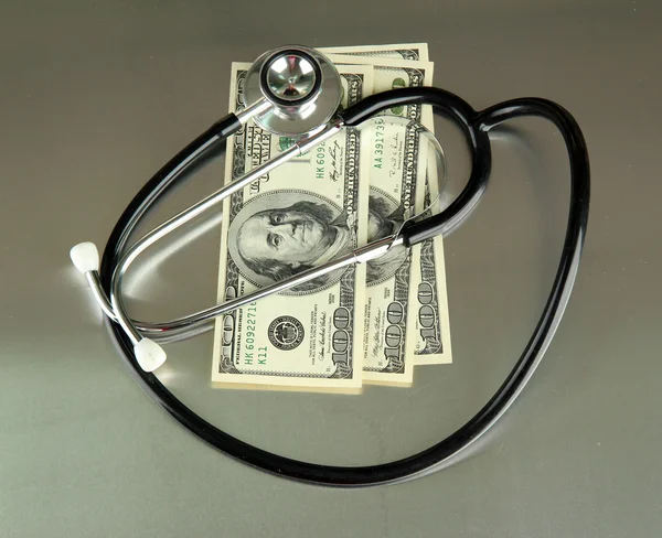 Conceito de custo de cuidados de saúde: estetoscópio e dólares em fundo cinza — Fotografia de Stock