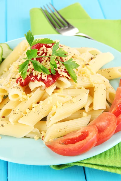Rigatoni pasta dish with tomato sauce on blue wooden table close up — Stock Photo, Image