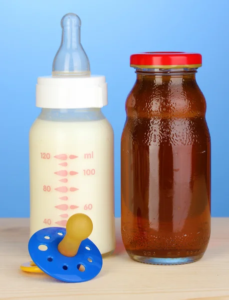 婴儿奶瓶的牛奶和果汁在蓝色背景上的 — 图库照片