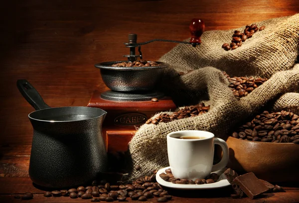 Coffee grinder, turk and cup of coffee on brown wooden background — Stock Photo, Image