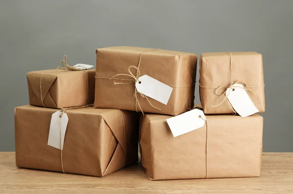 Boîtes de colis avec papier kraft, sur table en bois sur fond gris — Photo