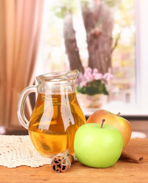 Full jug of apple juice and apple on wooden table on bright background — Stock Photo, Image