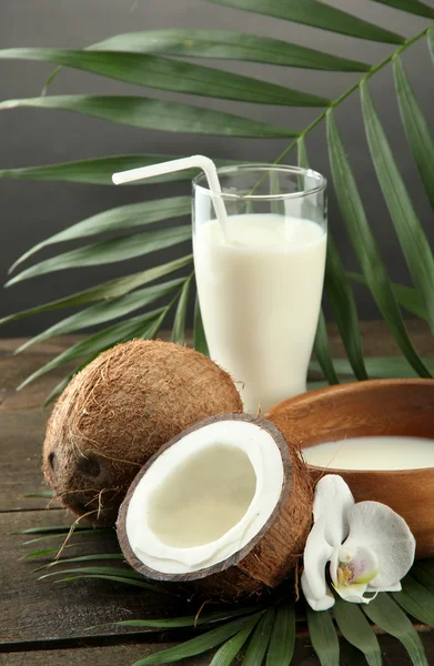 Kokosnöt med glas mjölk, på träbord, på grå bakgrund — Stockfoto