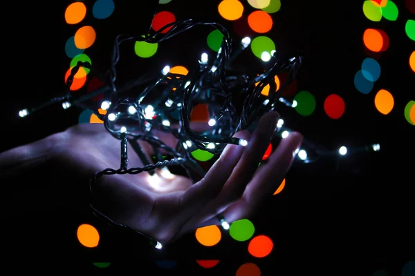 Weihnachtsbeleuchtung in der Hand auf verschwommenem Licht Hintergrund — Stockfoto