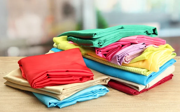 Heap of cloth fabrics on wooden table — Stock Photo, Image