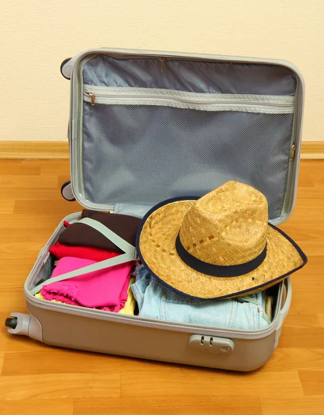 Open silver suitcase with clothing in room — Stock Photo, Image