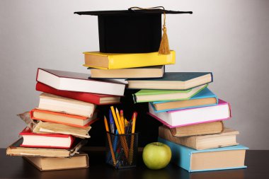 kitapları ve okul yönetimi gri arka plan üzerinde ahşap tablo karşı magister kap