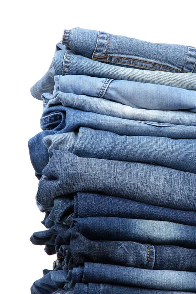 Molti jeans impilati in un mucchio isolato su bianco — Foto Stock