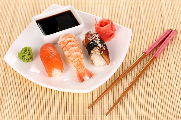 Delicioso sushi servido en el plato en la estera de bambú — Foto de Stock