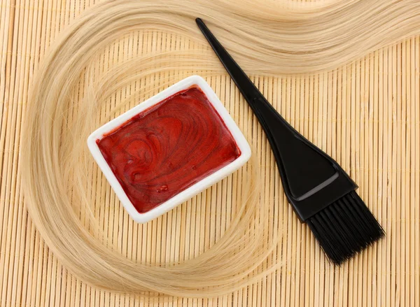 Hair dye in bowl and brush for hair coloring on beige bamboo mat, close-up — Stock Photo, Image