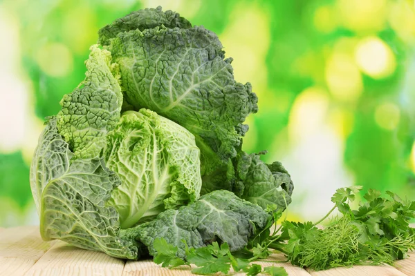 Fresh savoy cabbage on wooden table on natural background — Stok fotoğraf