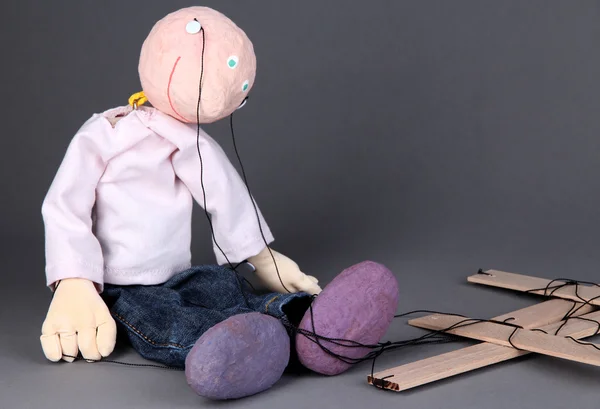 Marionetta in legno seduta su sfondo grigio — Foto Stock