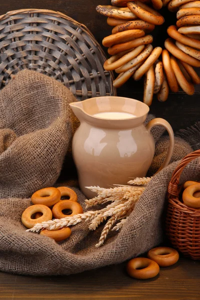 Pot van melk, smakelijke bagels en spikelets op houten achtergrond — Stockfoto