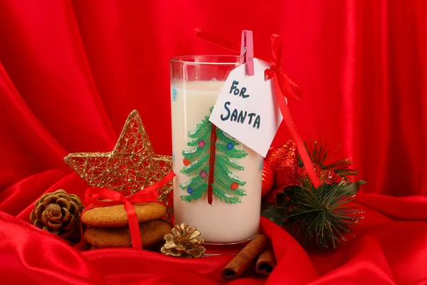 Cookies voor santa: Conceptuele afbeelding van gember koekjes, melk en kerst decoratie op rode achtergrond — Stockfoto