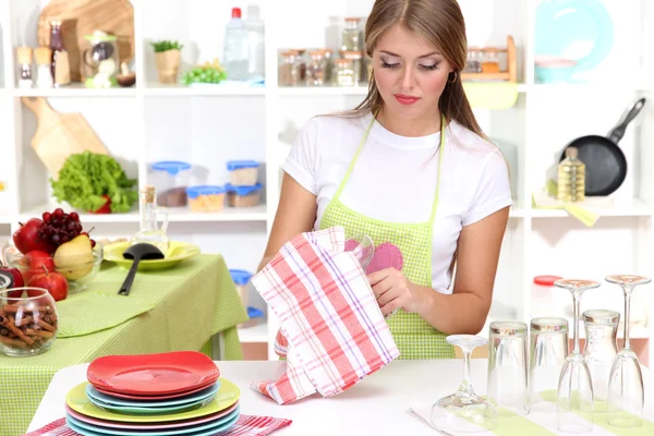 Una giovane ragazza asciuga i piatti in cucina — Foto Stock