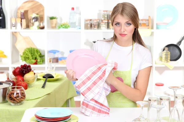 Una chica joven seca platos en la cocina —  Fotos de Stock