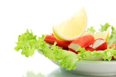 Yengeç sopalarla marul yaprakları ve plaka üzerinde beyaz izole limon